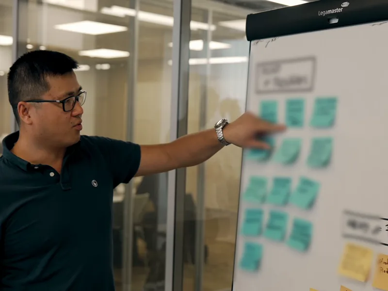 Stéphane Thanasack, coach produit, montre des post-its sur un tableau de priorisation pendant un atelier.